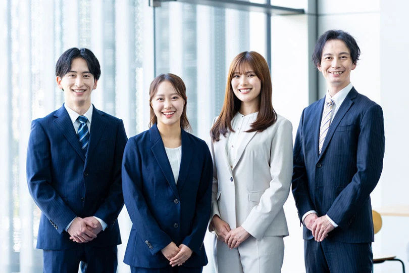 オフィスで並んで立つ4人の若手社員