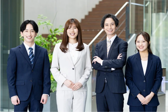 若手社員が並んで笑顔で立つ集合写真